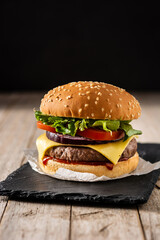 Cheeseburger with beef,tomato, lettuce and onion on wooden table