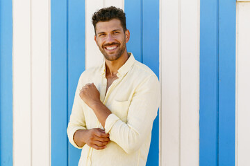 Young man, fashion model, posing in front of a beach booth.