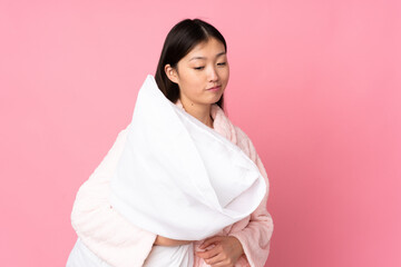 Fototapeta premium Young Asian woman in pajamas isolated on pink background with sad expression
