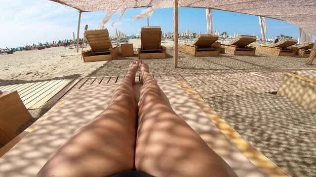 Happy attractive hispanic multiracial woman lying down on beach luxury resort enjoying sun tanning sunbathing in swimsuit, relaxing on Caribbean tropical beach summer vacation
