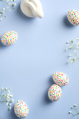 Happy Easter concept. Flat lay composition with Easter eggs, bunny and flowers on pastel blue background. Creative design.