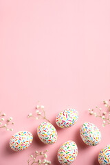 Happy Easter concept. Flat lay Easter eggs on pastel pink background with flowers. Top view with...