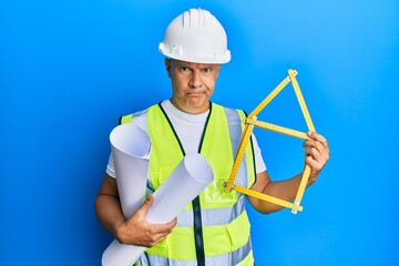 Middle age bald man wearing architect hardhat holding build project skeptic and nervous, frowning upset because of problem. negative person.