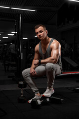Fototapeta na wymiar Handsome man with big muscles, posing at the camera in the gym. model in white sportswear