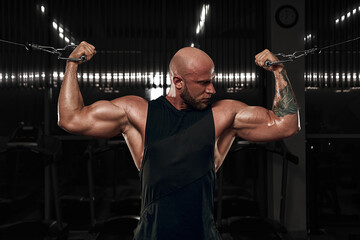 Fototapeta na wymiar Bodybuilder male model training biceps muscles with dumbbell. model in black shirt