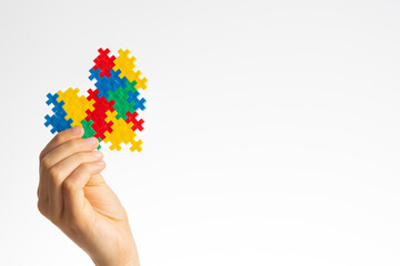 World autism awareness day concept. Child hands holding colorful puzzle heart on white background