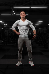Fototapeta na wymiar Handsome man with big muscles, posing at the camera in the gym. model in white sportswear