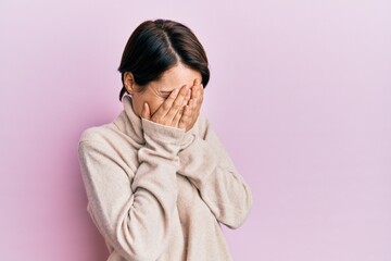 Young brunette woman with short hair wearing casual winter sweater with sad expression covering face with hands while crying. depression concept.