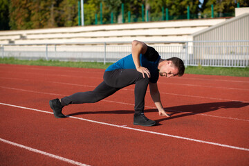 Fototapeta premium Athletic guy doing stretching after jogging