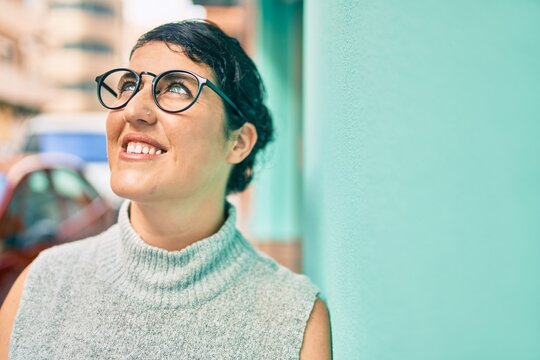 Young plus size woman smiling happy leaning on the wall at the city.