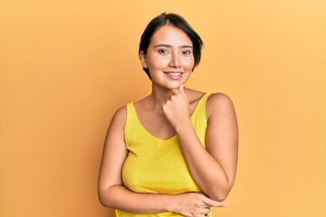 Obraz premium Beautiful young woman with short hair wearing casual clothes smiling looking confident at the camera with crossed arms and hand on chin. thinking positive.