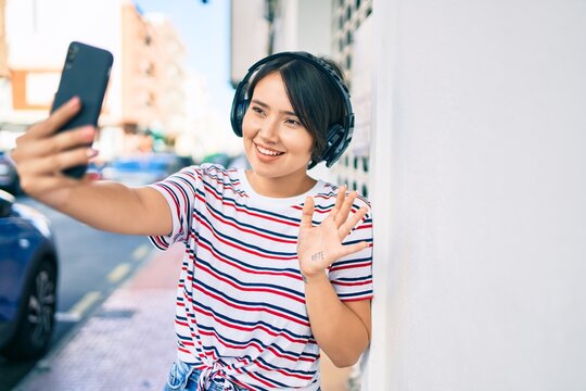 Young latin girl smiling happy doing video call using smartphone and headphones at the city
