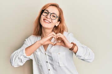 Young caucasian woman wearing casual clothes and glasses smiling in love doing heart symbol shape with hands. romantic concept.
