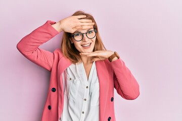 Young caucasian woman wearing business style and glasses smiling cheerful playing peek a boo with hands showing face. surprised and exited