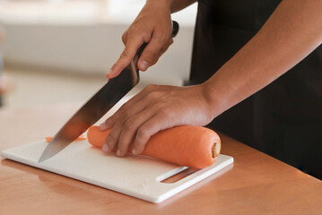 A man cutting carrots, he is cooking in his home kitchen, he spends time working from home in his own cooking practice, cooking training ideas.