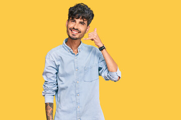 Young hispanic man wearing casual clothes smiling doing phone gesture with hand and fingers like talking on the telephone. communicating concepts.