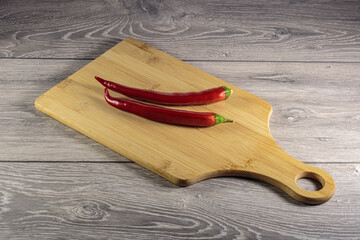 Pods of hot red pepper on the cutting board.