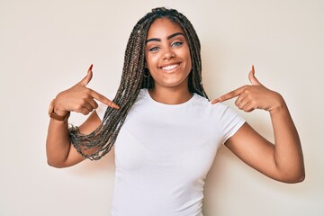 Young african american woman with braids wearing casual white tshirt looking confident with smile...
