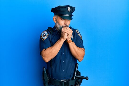 Middle age handsome man wearing police uniform laughing nervous and excited with hands on chin looking to the side
