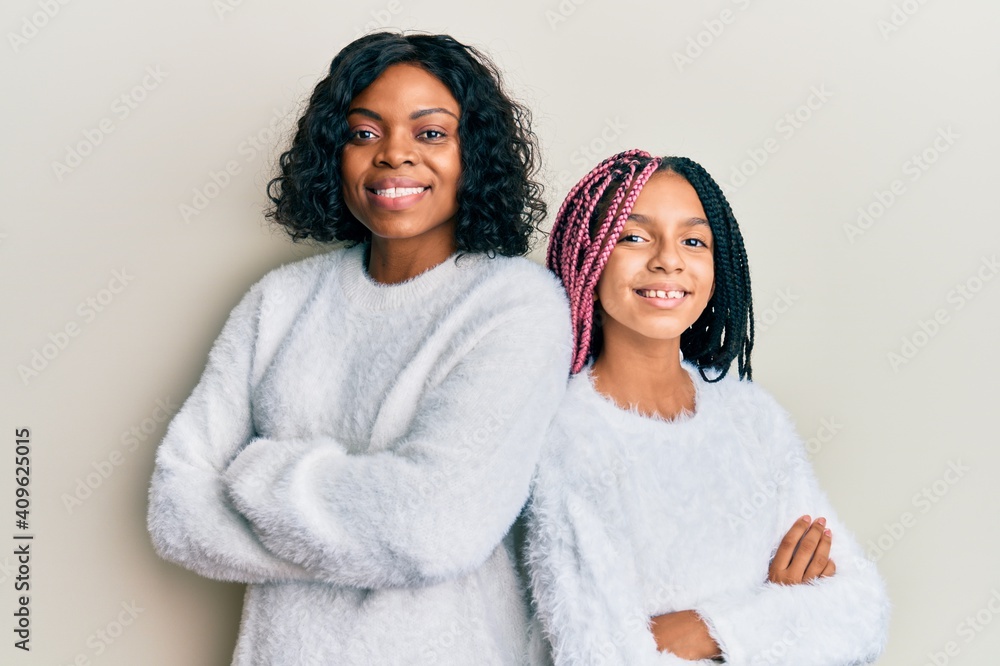 Wall mural Beautiful african american mother and daughter with arms crossed gesture smiling with a happy and cool smile on face. showing teeth.