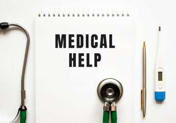 MEDICAL HELP text written in a notebook lying on a desk and a stethoscope.