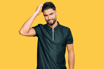 Young man with beard wearing sportswear confuse and wonder about question. uncertain with doubt,...