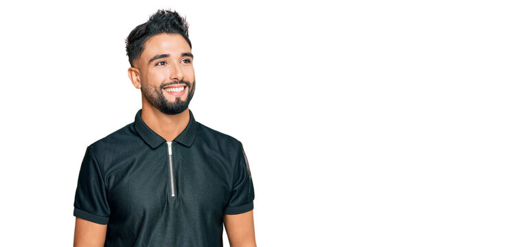 Young man with beard wearing sportswear looking away to side with smile on face, natural expression. laughing confident.