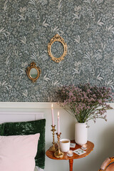 White vase with dried flowers on the table near the bed in the bedroom