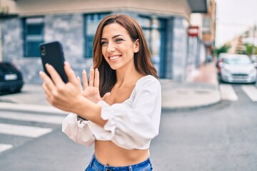 Young hispanic woman smiling happy doing video call using smartphone at the city.