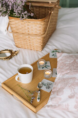 Fototapeta na wymiar Tray with a mug of tea and candles on the bed Basket with dried flowers
