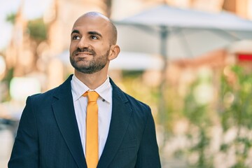 Young hispanic bald businessman smiling happy standing at the city.