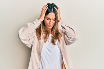 Brunette young woman wearing casual clothes suffering from headache desperate and stressed because pain and migraine. hands on head.