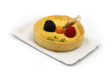 delicious mini cake with fresh fruits of physalis, blackberry and raspberry on paper plate isolated on white