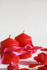 two red candles tied with a red ribbon, heart, roses on a white background, top view