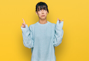 Young hispanic woman wearing casual clothes pointing up looking sad and upset, indicating direction...