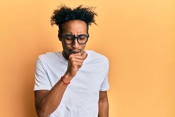 Young african american man with beard wearing casual white t shirt and glasses feeling unwell and...