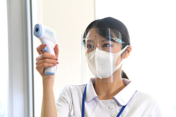  フェイスシールドを付けて検温する看護師