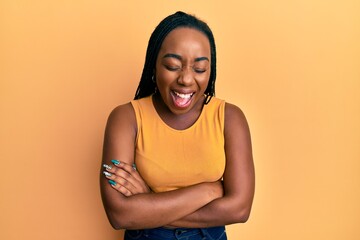 Obraz premium Young african american woman with arms crossed gesture smiling and laughing hard out loud because funny crazy joke.