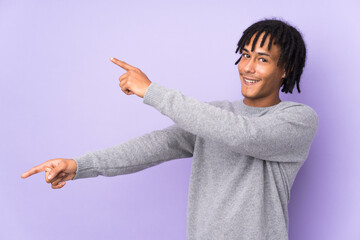 Young african american man isolated on purple background pointing finger to the side and presenting...