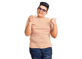 Fototapeta premium Little boy kid wearing casual clothes and glasses pointing to the back behind with hand and thumbs up, smiling confident