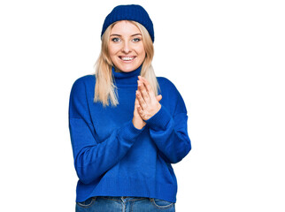 Young caucasian woman wearing wool winter sweater and cap praying with hands together asking for forgiveness smiling confident.