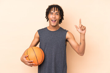Young african american man isolated on beige background playing basketball and having an idea