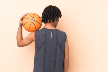 Young african american man isolated on beige background playing basketball in back position
