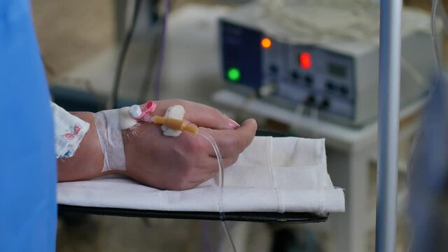 Hand with a patient catheter on the operating table against the background of electronic medical equipment. Doctor surgeon performs a surgical operation patient under general anesthesia