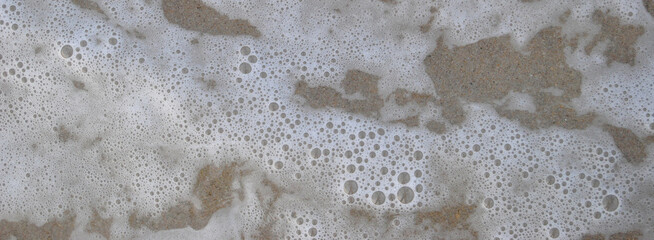 Textura  de água do mar com espuma, bolhas e areia de fundo