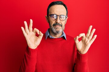 Fototapeta premium Middle age hispanic man wearing casual clothes and glasses relax and smiling with eyes closed doing meditation gesture with fingers. yoga concept.