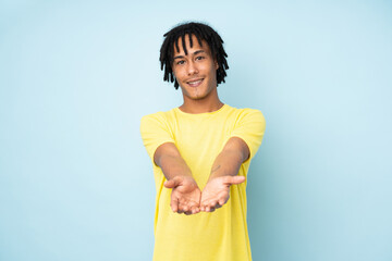 Young african american man isolated on blue background holding copyspace imaginary on the palm to...