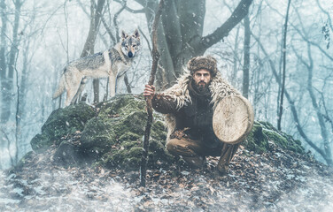 Shamanic man playing on shaman frame drum in the nature.