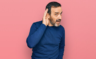 Middle age hispanic man wearing casual clothes smiling with hand over ear listening an hearing to rumor or gossip. deafness concept.