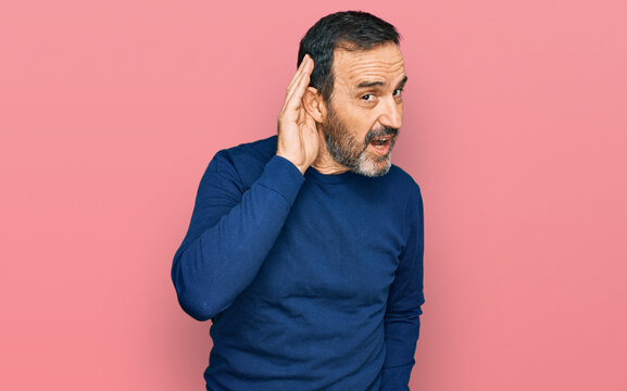 Middle age hispanic man wearing casual clothes smiling with hand over ear listening an hearing to rumor or gossip. deafness concept.